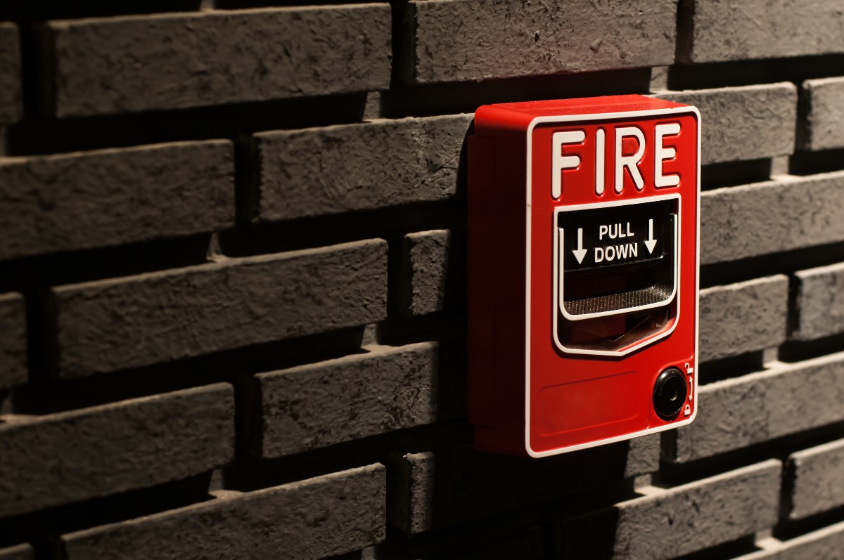 Close up of a fire alarm on a brick wall.