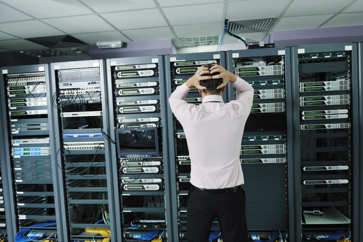 A man in a suit grabbing his hair in frustration while staring at on-premise servers
